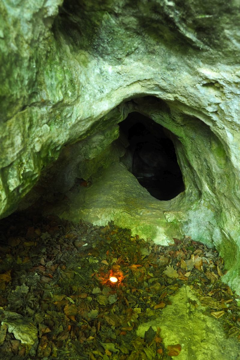 Jeskyně Slezákova díra - Záhrobní. Vchod jeskyně v místě  dětského neolitického hrobu (označeno plamenem svíčky). Foto: Marek Gyaneshwarpuri 2020.